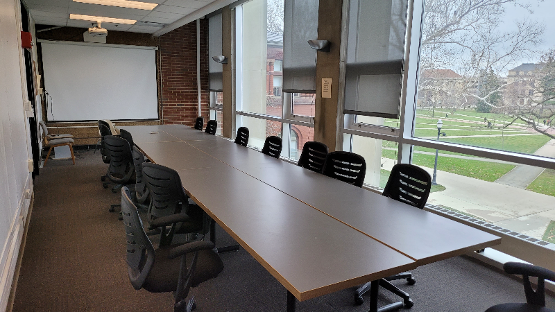 A room with a long conference table and large window facing the oval