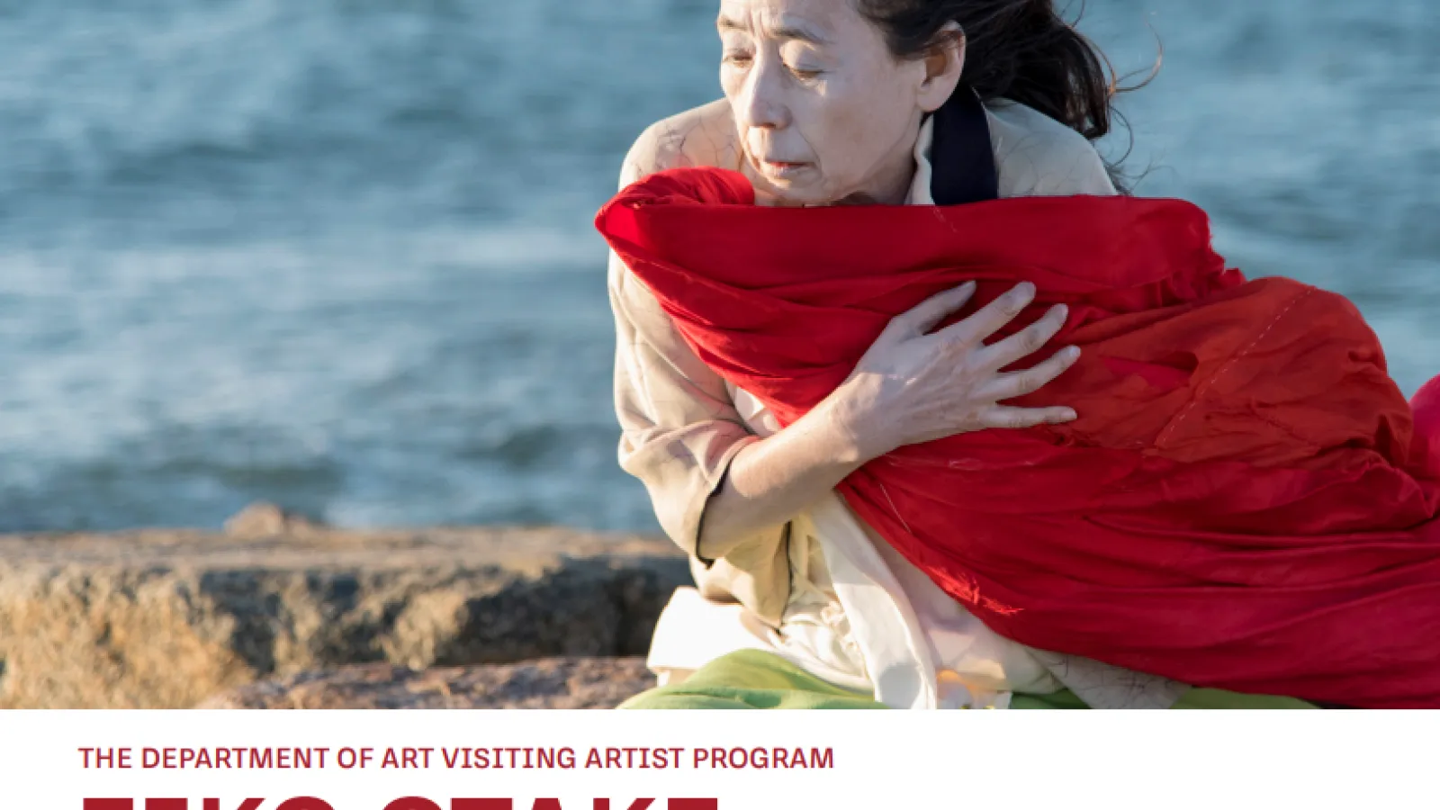 woman with downcast eyes and face on a beach wrapped in red cloth