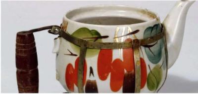 a ceramic pot, with wood handle on the left of the image, painted