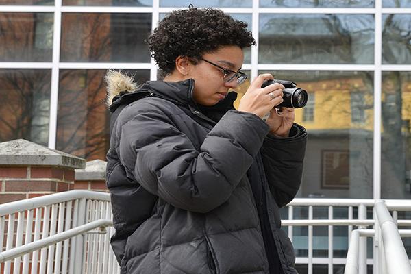 Student adjusting digital camera to shoot