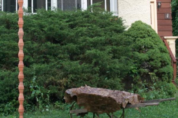 a metal sculpture in front of green bushes