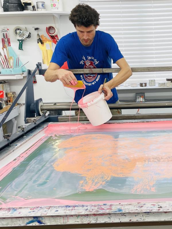a man with dark hair working in a printmaking studio