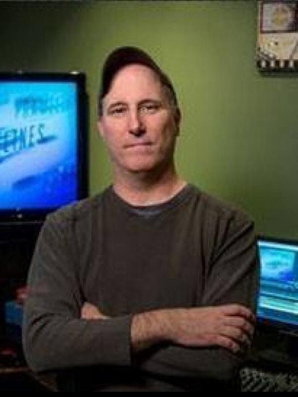 a white man with a baseball cap standing with arms crossed